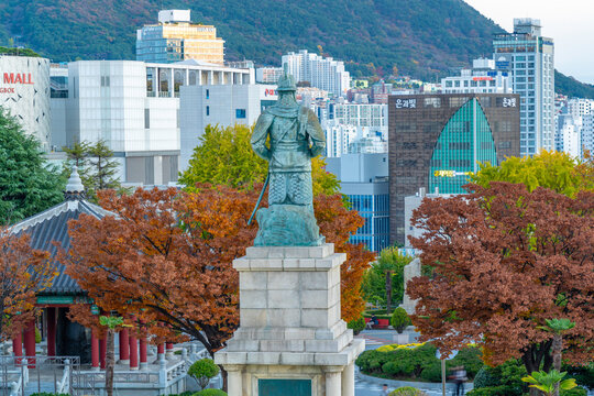 View of Statue of Admiral Yi Sun-sin in Yongdusan Park and city skyline at sunset, Busan, South Korea