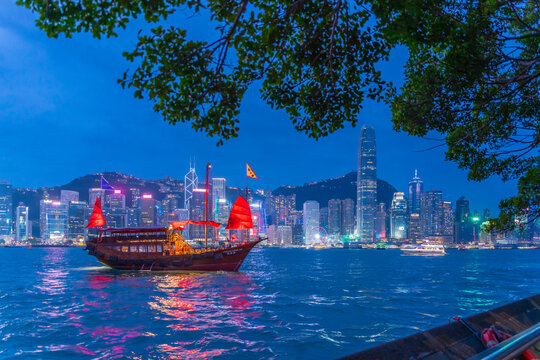 View of Hong Kong skyline and red sail junk boat from Kowloon at dusk, Kowloon, Hong Kong, China