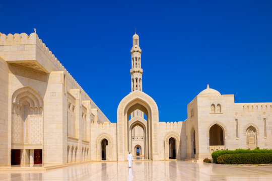 Muslim worshipper walking through the courtyard of Sultan Qaboos Grand Mosque in Muscat, Oman during daylight