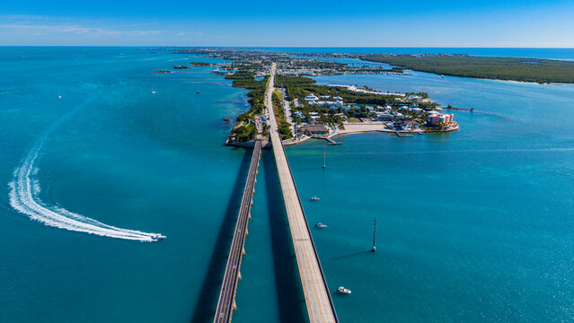 Sunlight reflects on clear waters near Highway Number 1 with vehicles traveling on 7 Mile Bridge in Florida Keys