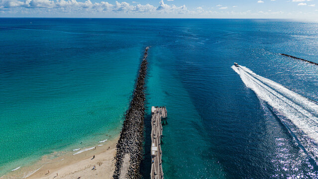 Coastline view of South Beach point with jetty, sandy beach, and boat in water in Miami, Florida