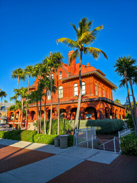 Red historic building surrounded by palm trees in Florida with blue sky