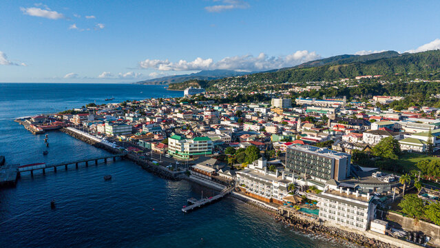 Colorful buildings line the waterfront in a busy town with mountains in the background on a clear day in the Caribbean