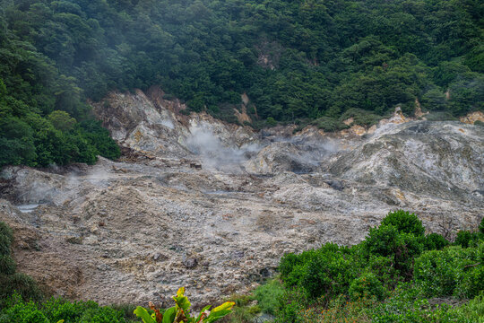 Visit drive in volcano with steam and volcanic rocks near thick vegetation in Saint Lucia