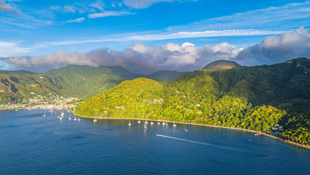 Lush green landscape along the coast with boats in the water near a hillside in Saint Lucia