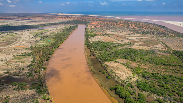 Aerial view of Juba river winding through landscape with vegetation and coastal area in the distance near Kismayo, Somalia