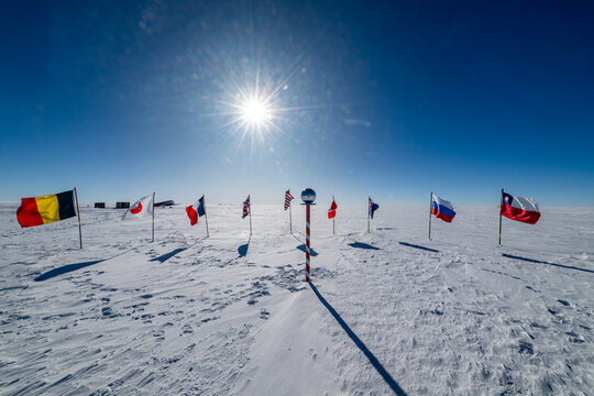 Flags from various countries stand on snow-covered ground at the South Pole, Antarctica