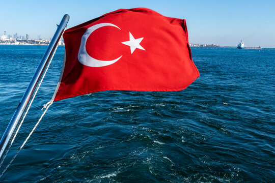 Flag of Turkiya waving from a boat on the Bosphorus with Istanbul skyline in the background