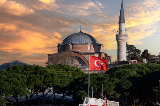 Sunset view of Rum Mehmed Pasha Mosque with national flag in foreground in Istanbul, Turkey