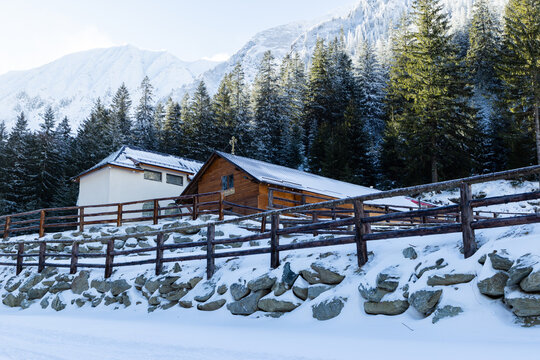 Trekking along the snow-covered path near traditional cabins in a winter landscape in Romania