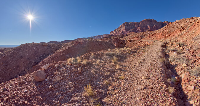 Trail leads through rocky landscape under bright sun at Vermilion Cliffs National Monument in Arizona