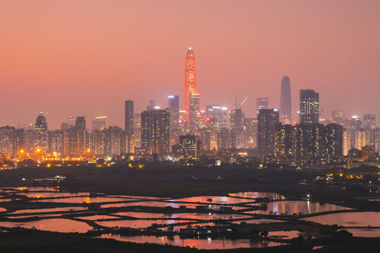 View of Shenzhen skyline from Former Macintosh Fort hill at sunset with city lights and reflections in water near Ma Tso Lung