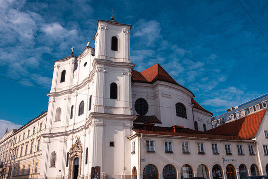 Baroque facade of Trinitarian Church in Bratislava shines under blue sky near Presidential Palace