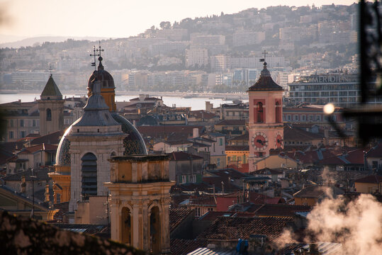 Rooftop view highlights church domes and buildings in Old Town above Mediterranean coastline in Nice, France