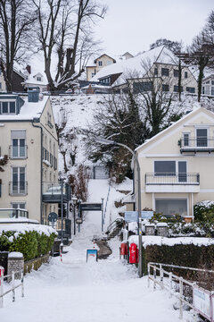 Snow-covered stairway leads to hillside homes in a winter scene along the Elbe River in Hamburg, Germany