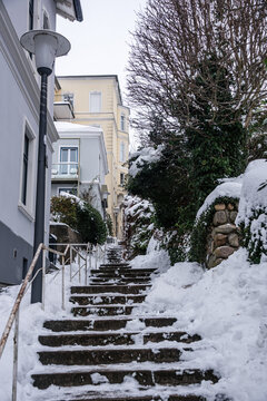 Snow-covered stairs climb through a steep footpath with stone walls in winter time in a district in Hamburg, Germany