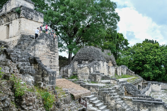 Visitors explore stone buildings in Central Acropolis at Tikal, reflecting ancient Maya urban planning and architecture in Guatemala