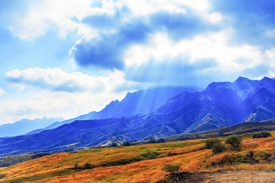 Sun-rays break through clouds illuminating autumn hills in Aso, Kumamoto Prefecture, Kyushu, Japan