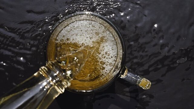 Overhead View of Golden Beer Pouring into Glass Mug on Wet Surface