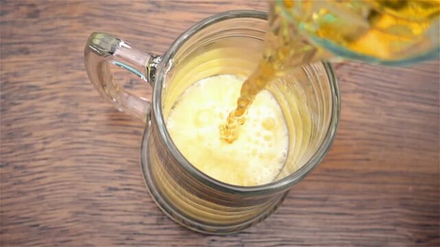 Pouring Fresh Golden Lager into Glass Mug on Rustic Wood Table