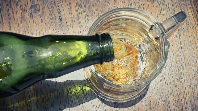 Top Down View of Cold Beer Pouring into Glass Mug with Frothy Foam