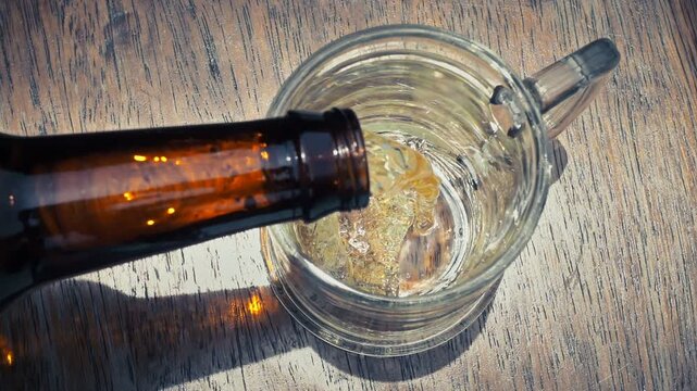 Top Down View of Cold Beer Pouring into Glass Mug with Frothy Foam