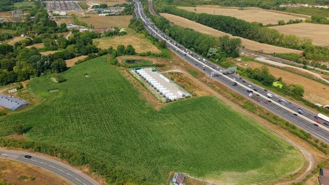 Aerial panning view across renewable battery storage facility and surrounding M1 motorway transport hub in Bedfordshire
