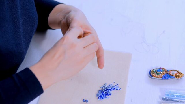 Jewelry designer making handmade eardrop earring accessory in creative craft studio workshop in 4K Ultra HD footage.
