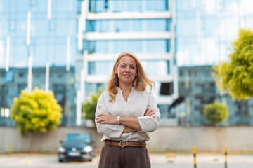 Fototapeta premium Confident businesswoman with arms crossed standing outside office building