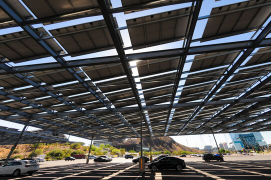 Solar panel canopies covering a parking lot with vehicles beneath, illustrating renewable energy, shaded parking, solar power generation, and sustainable infrastructure