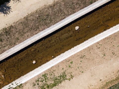 Drone view shows river management efforts with channel widening and flood prevention features in a rural area during daytime.