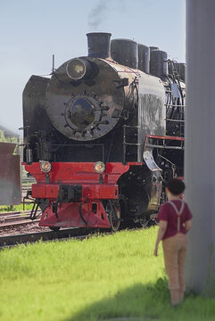 A vintage steam locomotive against a summer landscape. The power of a steam locomotive: a close-up of the locomotive's front end.