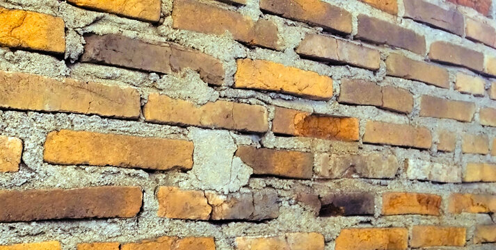 Rustic red brick wall with a weathered appearance.