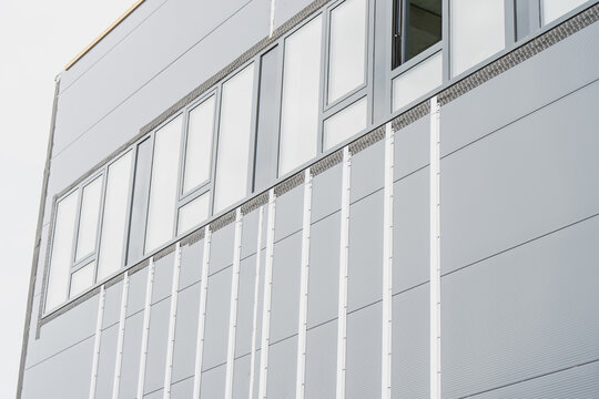 Insulated metal facade panels with vertical joint trims and architectural window assemblies on an industrial commercial building