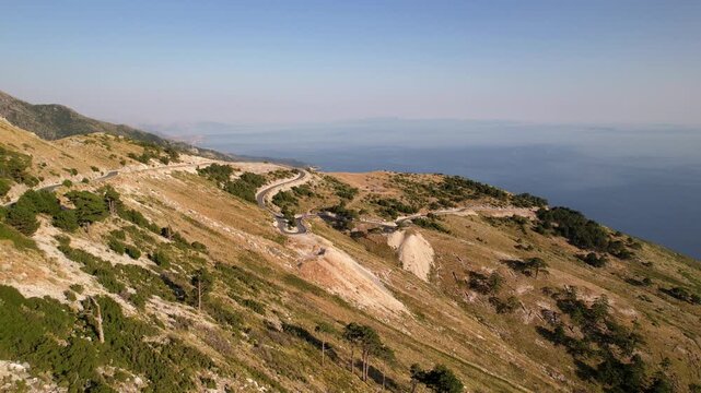 Aerial view of the winding Llogara Pass mountain road near Vlora and Zeus mountain, amazing scenery view. Aerial panoramic drone view from above, top view from drone. 
