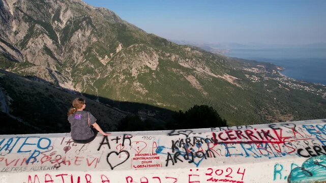 Woman on observation deck mountain in albania near Llogara Pass mountain road near Vlora and Zeus mountain, amazing scenery view. Aerial panoramic drone view from above, top view from drone. 