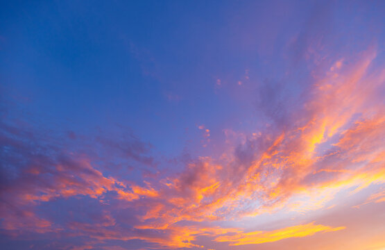 Vibrant Golden Sunset and Purple Twilight Sky with Clouds,Stunning and vibrant sunset sky filled with dramatic golden orange clouds contrasting against a deep blue and purple twilight background, 