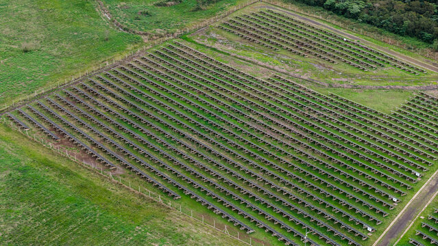 Aerial view of a large solar farm with rows of photovoltaic panels installed in a green grassy field in Posadas, Misiones Province, Argentina.
