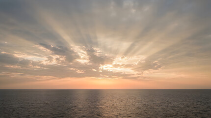 Fototapeta premium Dramatic ocean sunset with golden sun rays over calm sea horizon at dusk