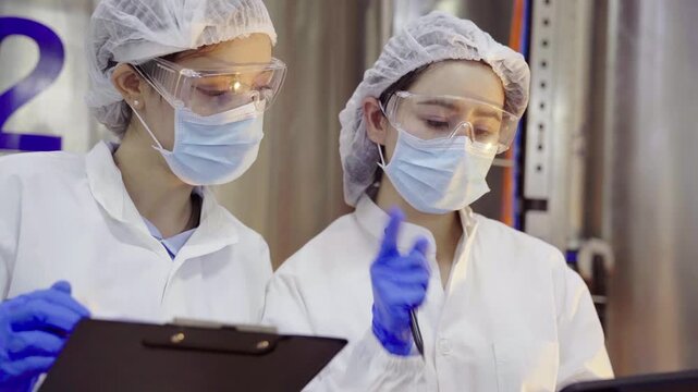Female quality control inspectors checking food processing machinery