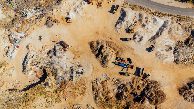 Aerial view of a quarry site with heavy machinery, piles of gravel, sand, and excavated earth in Rab, Primorje-Gorski Kotar, Croatia.