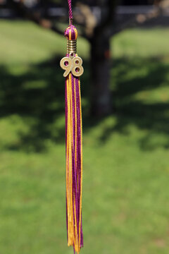 Purple and gold 1998 graduation tassel hanging outdoors