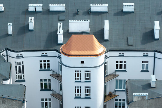 Aerial view of a fully renovated residential building with a copper-colored roof, white facade, and multiple chimneys in Poland.
