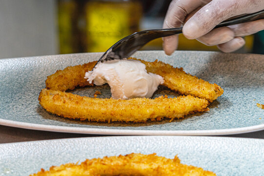  Professional chef hands plating a gourmet grilled banana dessert with vanilla ice cream and rich chocolate sauce.