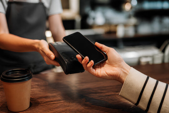 Business professional using smartphone at wooden table in modern caf&eacute; workspace