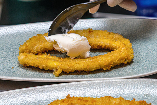  Professional chef hands plating a gourmet grilled banana dessert with vanilla ice cream and rich chocolate sauce.