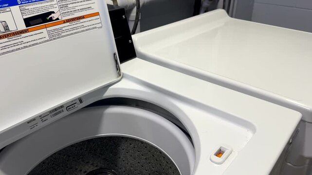 Female hand opening a top-loading washing machine in a modern American home. Horizontal 4K video showcasing laundry, household routine, home appliances, cleaning, convenience and everyday lifestyle