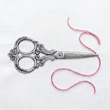 Top view of embroidered vintage scissors with a curling pink thread on a white fabric background. Ornate antique sewing tool rendered in textile art. Handmade needlework and tailoring craft concept