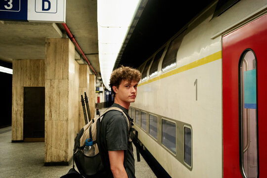 Young Man Waits on Train Platform in a City During the Day
