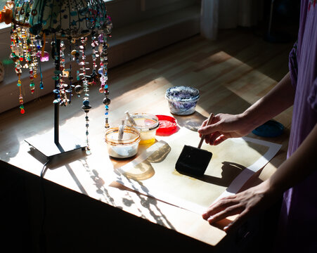 Artist Coating Paper for Cyanotype Printing in Sunlit Studio